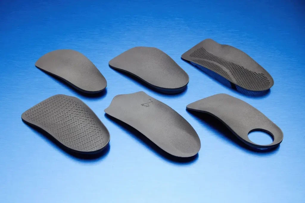 Six different styles of custom 3D printed orthotics showing varied designs for different foot types and conditions