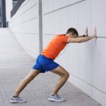 Runner stretching calf against a wall — sports injury prevention